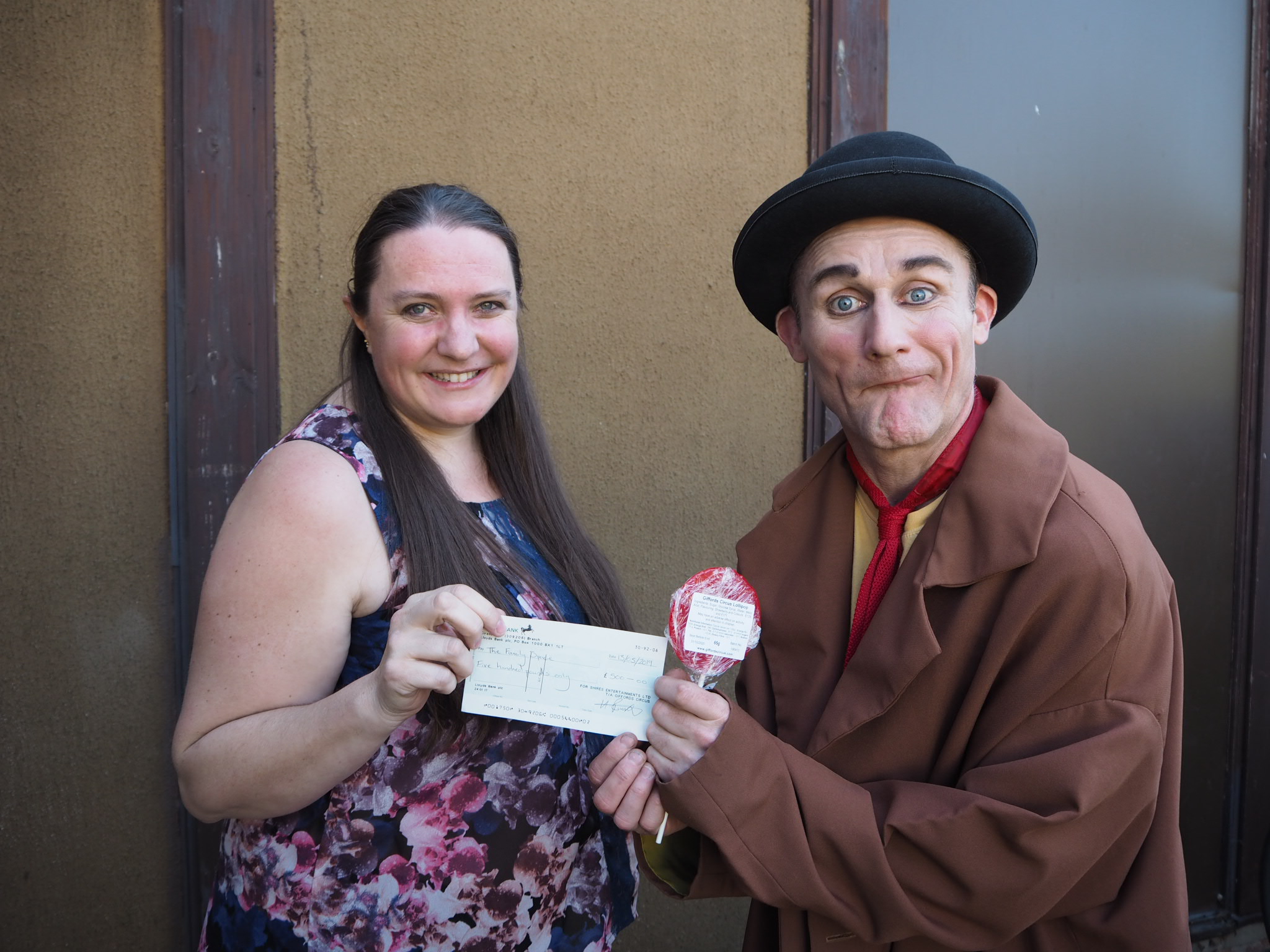 Tweedy of Giffords Circus presenting Sarah Avery, Manager of the Family Space with a cheque for £500